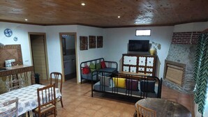 A cozy living room with a dining table, chairs, a sofa, and a TV.