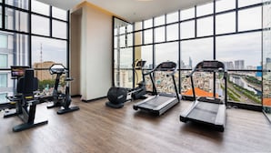 A gym with exercise equipment, large windows, and a city view.
