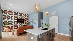 Una cocina moderna con una isla central, electrodomésticos de acero inoxidable y una pared azul.