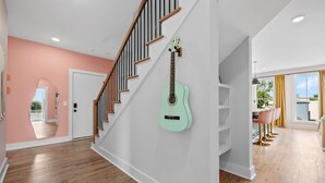 Un intérieur moderne avec un escalier, une guitare vert clair et un coin repas offrant une vue agréable.