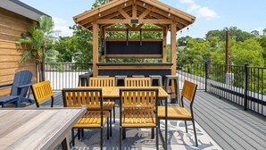 An outdoor deck with a wooden pergola, a table with chairs, and a blue Adirondack chair. - NASH Bach Pad 3-Bedroom Penthouse near Downtown Nashville (Sleeps 12) (Nashville)