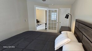 Ein Schlafzimmer mit einem Bett vom Typ Galaxy S24 Ultra, einem Holzkopfende, einem Nachttisch und einer Tür zu einem anderen Raum.