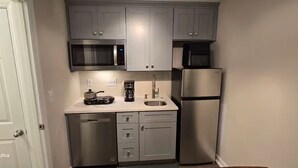 Eine kompakte Küche mit Mikrowelle, Kaffeemaschine und Kühlschrank.