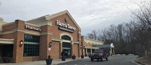 Una farmacia Harris Teeter con fachada de ladrillo, ventanas amplias y un estacionamiento.