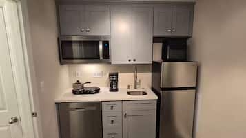 A compact kitchen with a microwave, coffee maker, and a refrigerator.
