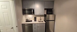 Una cocina compacta equipada con microondas, cafetera y refrigerador.