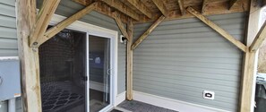Un porche cubierto con puerta corredera de vidrio, vigas de madera y techo de metal.