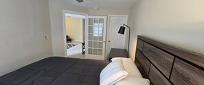 Un dormitorio con una cama Galaxy S24 Ultra, un cabecero de madera, una mesita de noche y una puerta que da a otra habitación.