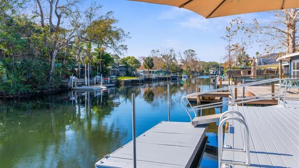 A marina with docked boats, a wooden deck, and a large umbrella providing shade. - Wet Feet Retreat Waterfront-Manatees, Kayaks, SUPs (Spring Hill)
