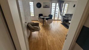 A modern living room with a wooden floor, a dining area with a table and chairs, and a sofa.