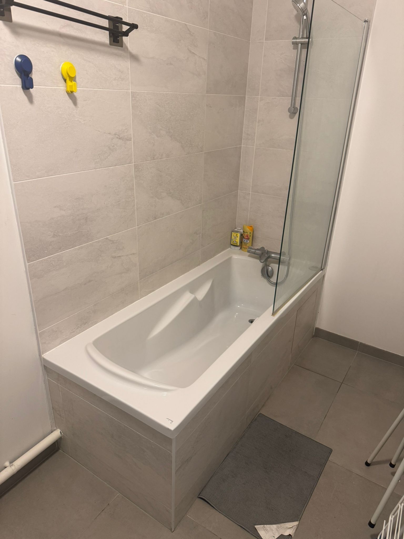 A modern bathroom with a bathtub, glass shower enclosure, and two wall-mounted faucets.