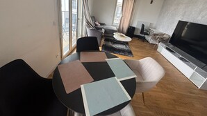 A modern living room with a round table, sofas, a TV, and large windows.
