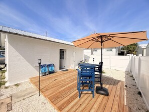En træterrasse med et bord, stole, en stor parasol og en lygtepæl.