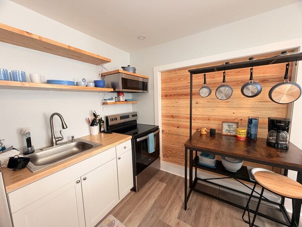 A modern kitchen with a wooden countertop, stainless steel appliances, and a hanging pot rack.