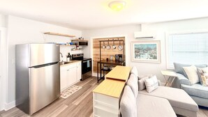 Una cocina moderna con refrigerador de acero inoxidable, armarios de madera y una zona de comedor con mesa y sofá de madera.