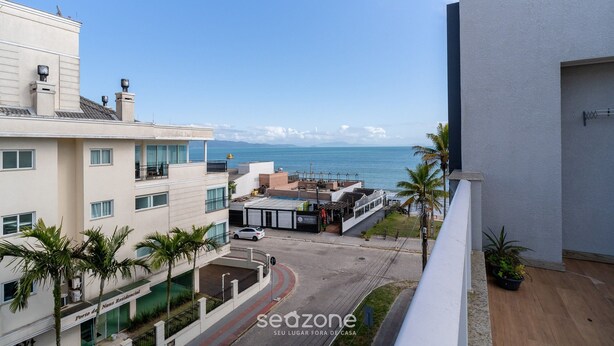 A residential building with a view of the sea, a parking area, and a few palm trees. - Apart With Sea View in Front of the Beach Pgl0301 (Florianópolis)