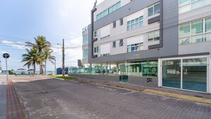 A modern building with a flat facade, large windows, and a sign indicating it is a Porto Gallery. - Apart With Sea View in Front of the Beach Pgl0301 (Florianópolis)