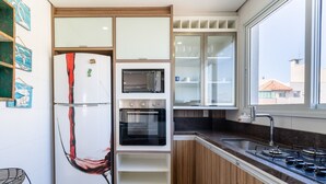 A modern kitchen with a refrigerator, oven, microwave, and gas stove. - Apart With Sea View in Front of the Beach Pgl0301 (Florianópolis)