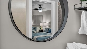 Une chambre à coucher avec un lit, un ventilateur de plafond, une table de chevet et un miroir.
