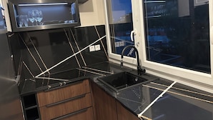 A modern kitchen with black countertops, a built-in oven, and a window with a view of the city. - Right in the town center, 5m from the beach on foot and 2m from the SNCF train station (Saint-Raphaël)