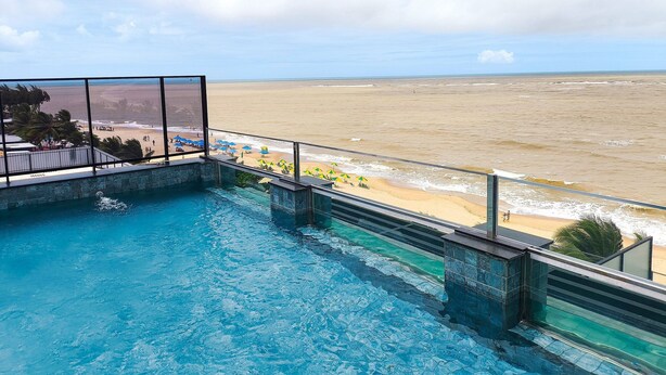 Una piscina con vista a una playa y al océano.