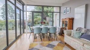Uma sala de estar moderna com área de jantar, janelas amplas e vista para o jardim.