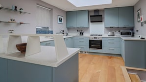 Cozinha moderna com armários azul-claros, claraboia e piso de madeira.