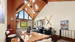 A cozy living area with a wooden ceiling, a dining table, and a ski-themed poster.