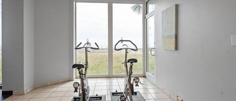 Een ruime kamer met twee vastgezet fietstoebehoren, grote ramen en een schilderij aan de wand.