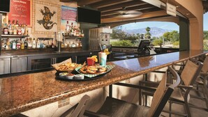 A bar area with a granite countertop, bar stools, a selection of drinks, and a view of mountains. - 1 Bedroom Villa at Marriott's Shadow Ridge II- The Enclaves (Palm Desert)