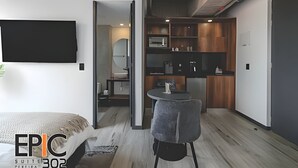Une chambre d’hôtel moderne équipée d’un lit, d’une petite table ronde et d’une kitchenette.