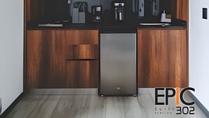 Une cuisine compacte dotée de meubles en bois, d’un réfrigérateur en acier inoxydable, d’un four à micro-ondes et d’une machine à café.