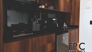 Une cuisine moderne avec des meubles en bois, un plan de travail noir et un four à micro-ondes encastré.