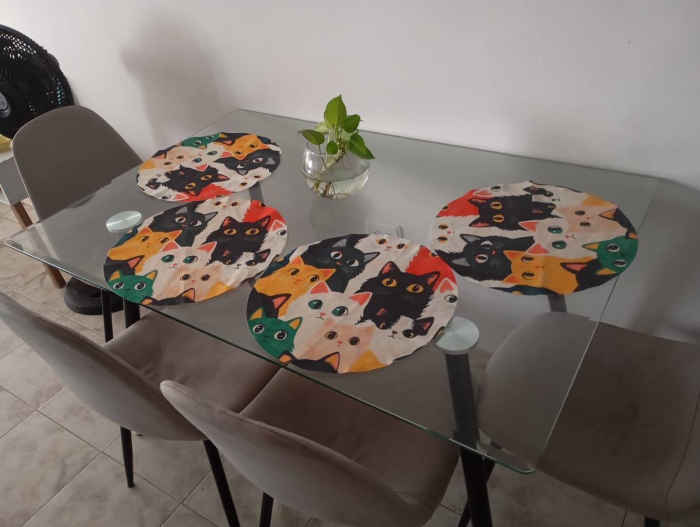 Une table de salle à manger avec un plateau en verre et un set de table à motifs félins.