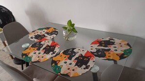 A glass-top dining table with a cat-themed placemat.