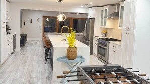 Een moderne keuken met witte kasten, een centraal eiland met een tafelvoetbalspel en een eethoek met een lichtblauwe tafel.