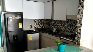 A modern kitchen with white cabinets, a black refrigerator, a sink, and a tiled backsplash. - @casa_grace Nice apartment with ocean view (Cartagena de Indias)