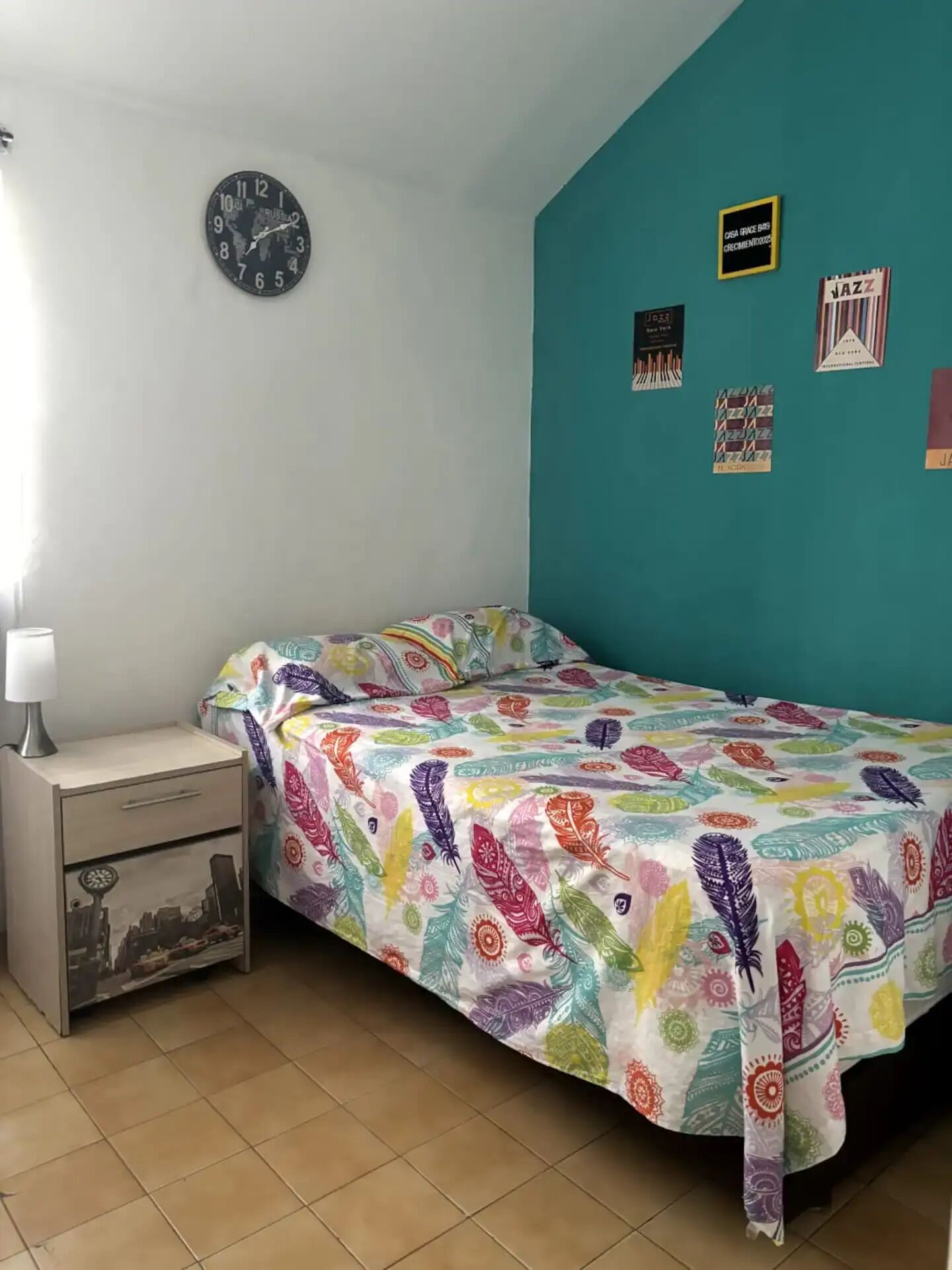 Ein Schlafzimmer mit einem Bett, einem Nachttisch, einer Wanduhr und Wanddekorationen.