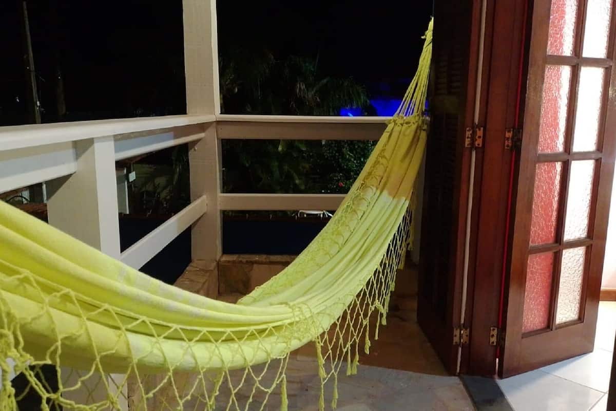 Una hamaca en un balcón con vista al cielo nocturno y una puerta que da al interior.