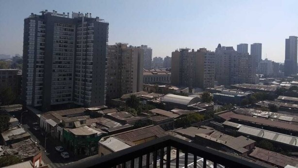 A high-rise building with multiple floors, surrounded by other buildings and a mix of residential and commercial structures. - Alojamientos On Santiago (Santiago)