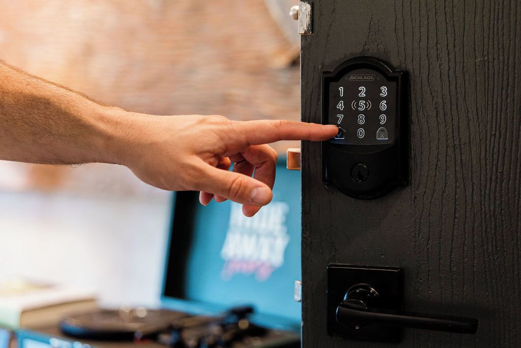 A hand pressing a numeric keypad on a door lock.