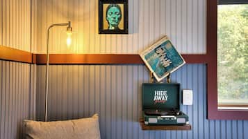 Een kamer met een gestreepte wand, een lijst met foto, een vintage platenspeler en een lamp.