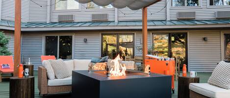 An outdoor patio with a fire pit, seating, and a covered area.