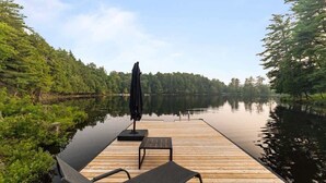 A wooden dock extending into a calm lake, surrounded by dense forest. - [Goldenwood] Luxury 5 BR Winter Retreat, Fireplace (Huntsville)