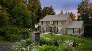 A two-story house with a stone entrance, a fire pit, and a well-maintained garden. - [Goldenwood] Luxury 5 BR Winter Retreat, Fireplace (Huntsville)