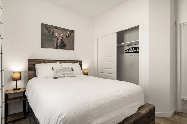 A neatly made bed with white linens, a wooden headboard, and a bedside lamp.