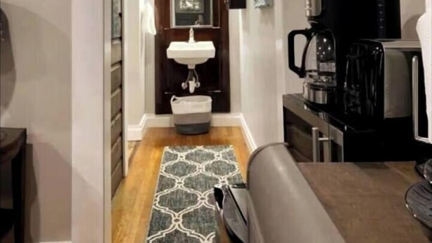 A narrow hallway leading to a bathroom with a sink, mirror, and a coffee maker. - Cottage Studio Suite # 1 (Fort Payne)
