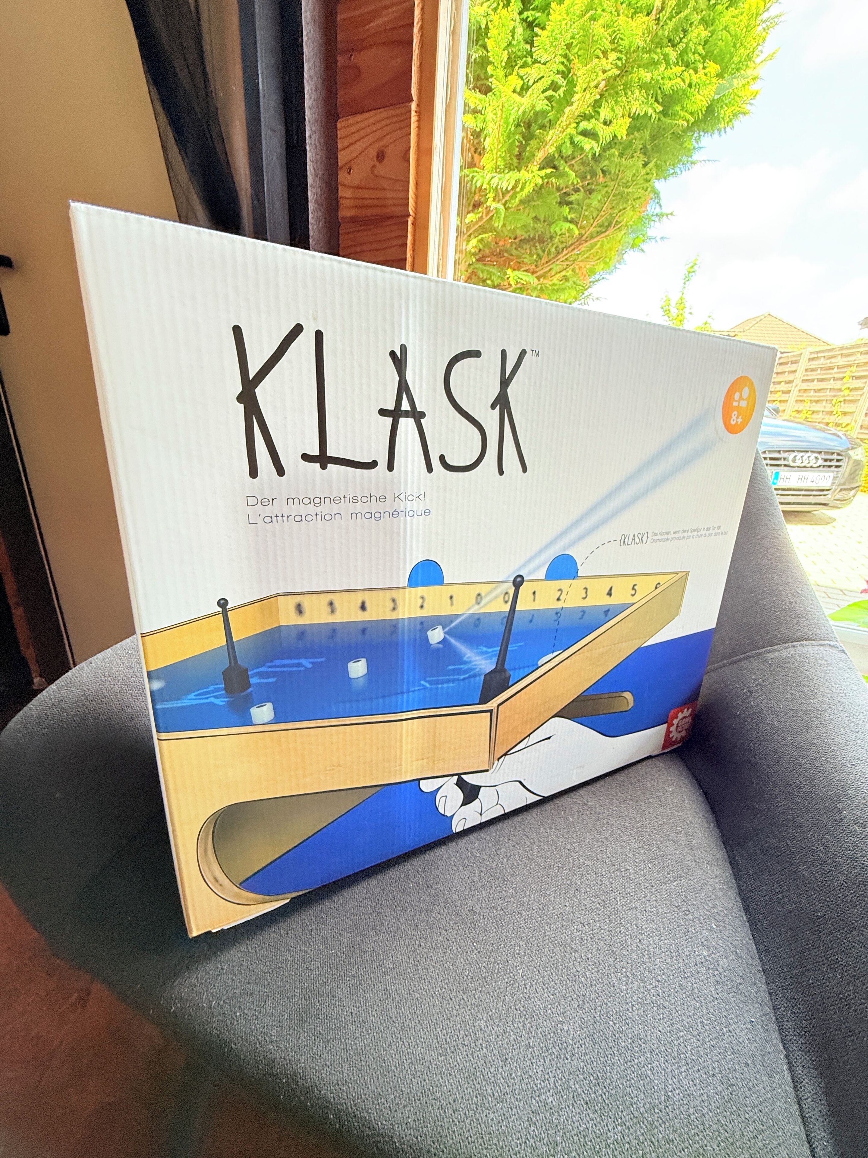 Une boîte étiquetée « KLASK », dotée d’une fonction d’attraction magnétique, posée sur une surface grise.