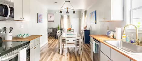 A modern kitchen with wooden flooring, white cabinetry, and a central island.