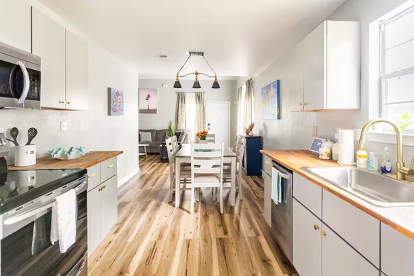 A modern kitchen with wooden flooring, white cabinetry, and a central island.